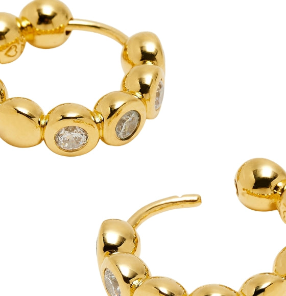 Gold hoop earrings with embedded gemstones on a white background