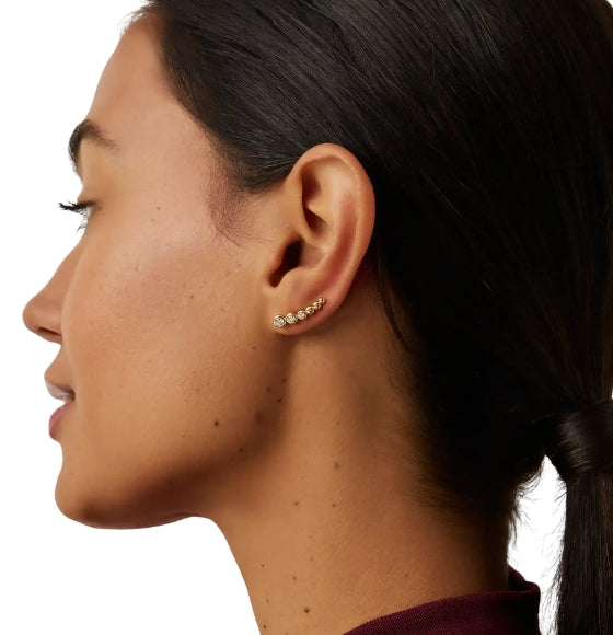 Close-up of a person wearing a gold earring on a white background