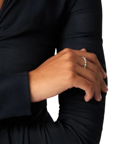 Person wearing a black long-sleeve shirt with a ring on a white background