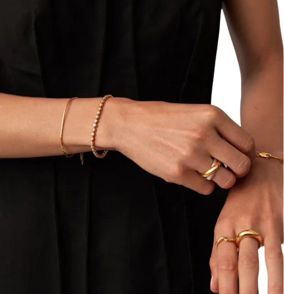 Close-up of hands wearing gold bracelets and rings