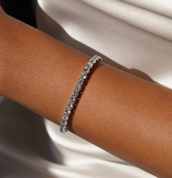 Silver bracelet on a person's wrist with a neutral background